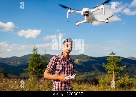 Uomo che aziona il controller del copter in montagna. Telecomando drone. Riprese aeree dei Carpazi estivi Foto Stock