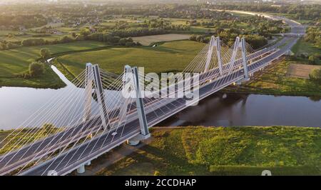 Ponte monumentale, illuminato, moderno e doppio con cavi sul fiume Vistola a Cracovia, Polonia, durante il tramonto. Costruzione industriale in calcestruzzo e acciaio Foto Stock