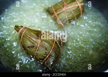 Primo piano gnocchi di riso (zongzi) in acqua bollente. Cibo cinese tradizionale al Dragon Boat Festival. Foto Stock