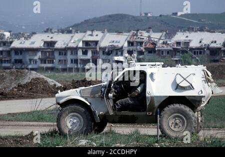 24 aprile 1994 durante l'assedio di Sarajevo: Su una Taxiway all'aeroporto, un Panhard APC francese è parcheggiato vicino ai blocchi di appartamenti in rovina di Dobrinja. Foto Stock