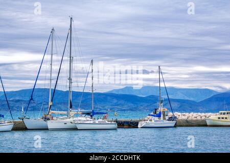 Isola di Corfù/Grecia - 4 maggio 2019: Vista sul bellissimo porto di Kerkyra – mare calmo, yacht bianchi e cielo blu con nuvole e montagne all'orizzonte. Foto Stock