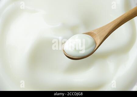 yogurt su cucchiaio di legno su sfondo yogurt Foto Stock