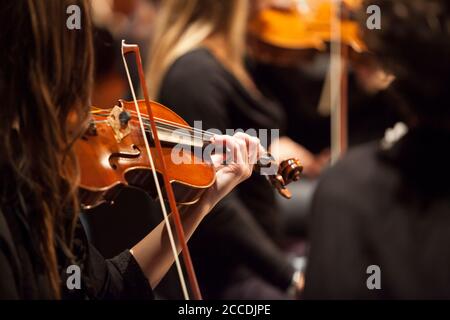 violinista di bruna femminile irriconoscibile che suona in un'orchestra professionale. Profondità di campo poco profonda. Foto Stock