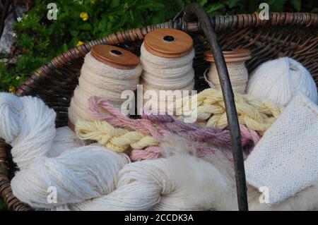 Un cesto di lana filata e tinta naturalmente, con un rolag di pile di Pickwick crudo pronto per la filatura in primo piano. Foto Stock