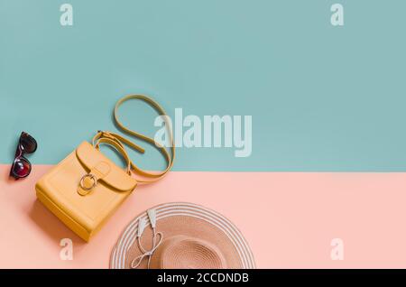 Bella paglia estiva con occhiali da sole e borsa arancione su sfondo chiaro. Concetto di vacanza, copyspace Foto Stock