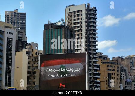 Beirut, Libano. 21 Agosto 2020. Un banner che recita 'Beirut non muore mai, Beirut è la signora dell'universea' è visto eretto di fronte a edifici pesantemente danneggiati vicino al sito del 4 agosto massiccia esplosione del porto. Più di due settimane dopo l'esplosione che ha scosso la capitale libanese alcuni residenti hanno cominciato a tornare a casa per la pulizia, la riparazione e per cercare di tornare alla loro vita normale. Credit: Marwan Naamani/dpa/Alamy Live News Foto Stock