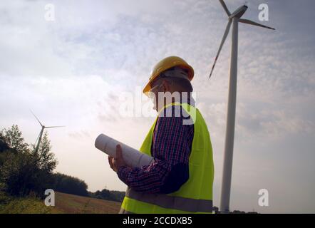 Ingegnere in una turbina eolica. Un uomo in un casco controlla il funzionamento dei mulini a vento elettrici. Concetto di ecologia e fonti energetiche rinnovabili. Foto Stock