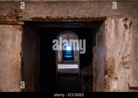 Orchha, Madhya Pradesh, India - Marzo 2019: Un corridoio arcuato scuro di un corridoio arcuato all'interno dell'antico palazzo di Jehangir Mahal nell'Orchha for Foto Stock