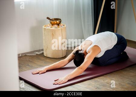 irriconoscibile giovane donna dp yoga esercizio, sedersi sul pavimento con la testa piegata alle gambe, meditare e stretching Foto Stock