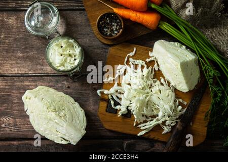 Sauerkraut preservando lo sfondo. Crauti fatti in casa con carote al pepe nero su rustico tavolo in legno. Cibo fermentato. Vista dall'alto sfondo piatto. Foto Stock