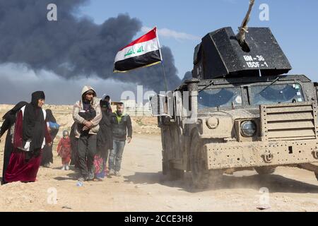 Mosul, Iraq. Il 7 marzo 2017 i civili fuggono dalle loro case vicino al quartiere di Tall ar Rayyan mentre un'Humvee delle forze speciali irachene passa a West Mosul. Credito: Giovane G. Kim Foto Stock