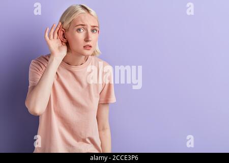 donna che tocca l'orecchio, la ragazza ha problemi con le orecchie, la salute. primo piano foto. copia spazio. che cosa hai detto Foto Stock