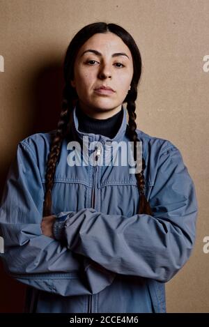 Ragazza con giacca blu e senza make up con la stessa acconciatura di Greta Thunberg, studio girato su sfondo di cartone marrone Foto Stock