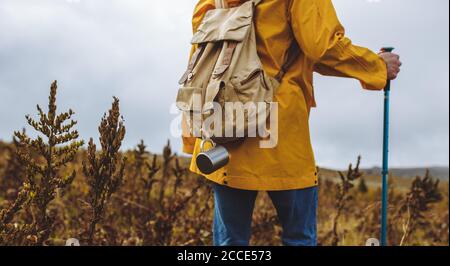 uomo escursionista con zaino che cammina attraverso il prato d'erba in una calda giornata d'autunno. indietro vista foto Foto Stock