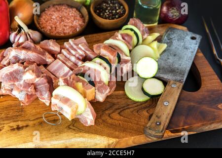 Pezzi di maiale crudi spiediti su bastoncini d'acciaio. Preparazione per barbecue estivo. Kebab di carne colorati preparati al momento con cipolla e pancetta. Carne cruda. Foto Stock