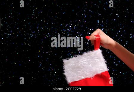 Donna che mette il regalo nel calzino di Natale appeso al camino a casa Foto Stock