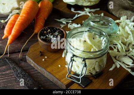 Sauerkraut preservando lo sfondo. Crauti fatti in casa con carote al pepe nero su rustico tavolo in legno. Cibo fermentato. Spazio di copia. Foto Stock
