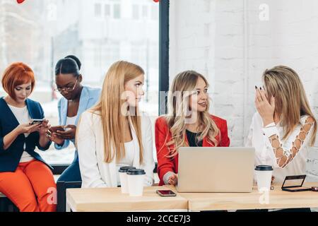 Gruppo di esperti femmina blogger sono copywriting per supporti pagina web digitando sulla tastiera del computer, seduti a tavola in ufficio. Foto Stock