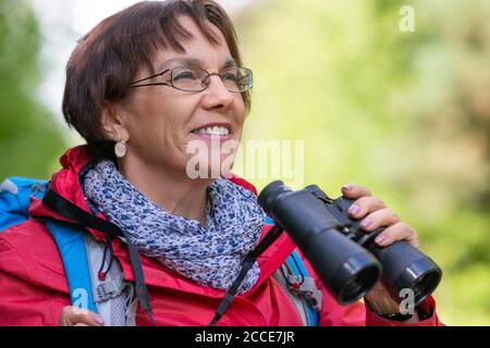 Primo piano ritratto di una donna anziana con binocoli all'aperto. Concetto di stile di vita attivo all'età dopo il 60. Foto Stock