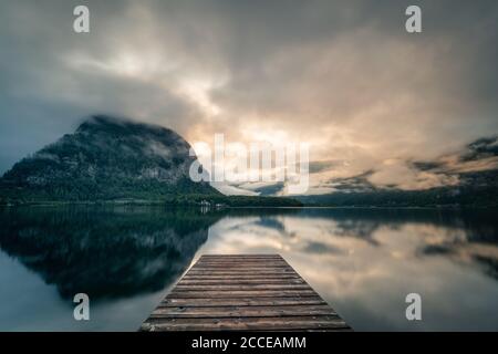 Riva sul lago di Hallstatt all'alba, molo sul lago, lago con riflessione Foto Stock