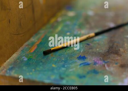 Pennelli su cavalletto colorati con vernici nello studio dell'artista. Foto Stock