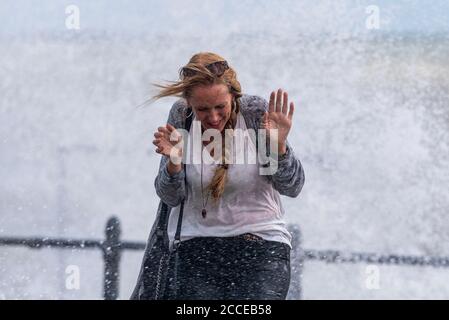 Bianca caucasica femmina bagnata da onde schiaccianti a Southend sul Mare, Essex, UK, durante gli alti venti di Storm Ellen. Scioccato dagli spruzzi Foto Stock