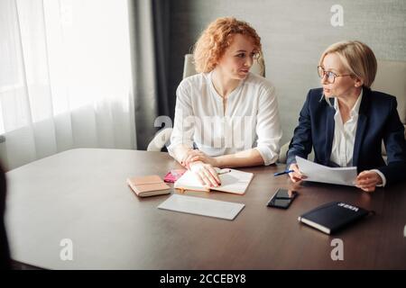 Due manager femminili delle risorse umane che conducono un colloquio di lavoro con una donna candidata in carica. Ottenere un nuovo concetto di lavoro Foto Stock