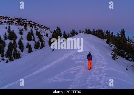 Europa, Svizzera, Vallese, Belalp, giovane donna sale su una cresta innevata e gode del tramonto su Belalp Foto Stock