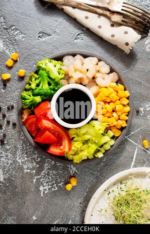 Ingredienti della cucina sul piatto. Vista dall'alto. Verdure, spezie, gamberi, salsa per cucinare. Foto Stock