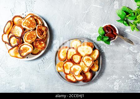 Mini frittelle sul piatto, tavolo con vista dall'alto su sfondo grigio. Foto Stock