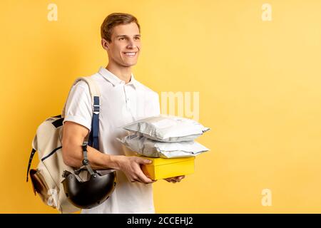ritratto di piacevole attraente ragazzo che lavora come corriere o consegna, trasportando le cose di imballaggio per il cliente, miglior lavoratore del mese nel servizio di consegna. Foto Stock