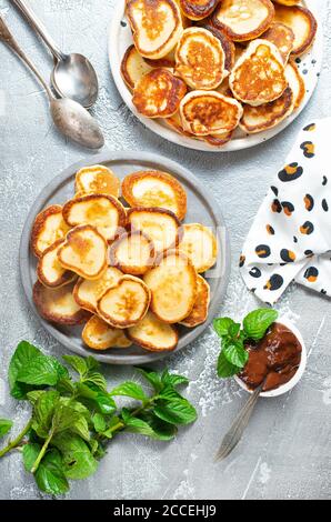 Mini frittelle sul piatto, tavolo con vista dall'alto su sfondo grigio. Foto Stock
