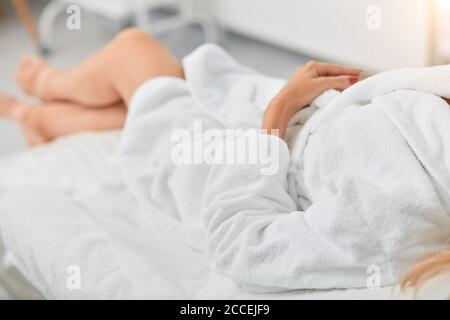 primo piano con foto ritagliate. donna in accappatoio bianco che si rilassa al resort. sfondo sfocato Foto Stock