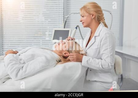 il giovane medico si è concentrato sulla pulizia del viso della donna. primo piano vista laterale foto Foto Stock