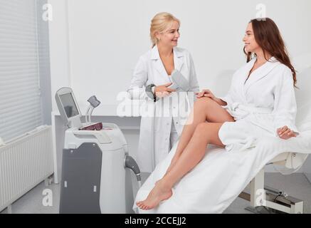 biondo medico e un cliente che ha una conversazione in clinica, primo piano foto Foto Stock