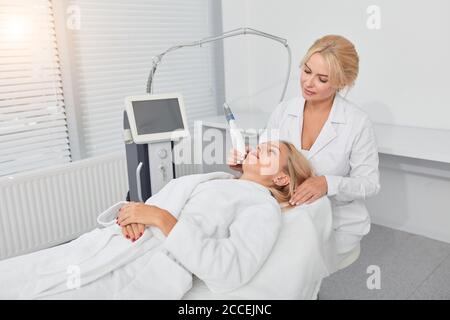 cliente biondo rilassato trattando il suo viso malsano in clinica moderna. primo piano foto Foto Stock