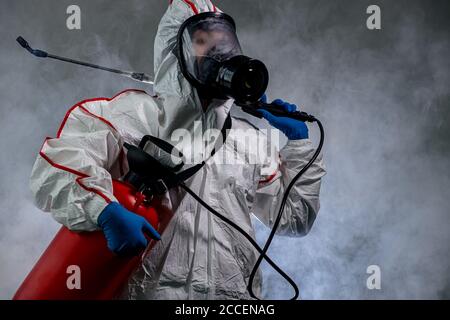 Ritratto di disinfettante professionale completamente armato contro COVID 10, utilizzando spray per la rimozione di batteri dalla superficie. Indossare maschera protettiva, guanti e Foto Stock