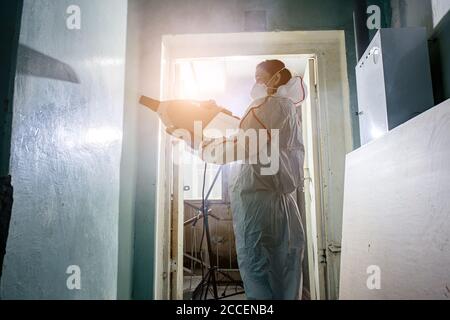 virologo in tuta protettiva per nocciolo conduce disinfezioni di superfici in luoghi pubblici e isolati, pandemia di rischio per la salute, coronavirus covid-19 conc Foto Stock