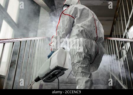 Disinfettante professionale in un dispositivo di protezione personale NBC tuta ppe, guanti, maschera, pulizia di spazi isolati con disinfettante spray pressurizzato w Foto Stock