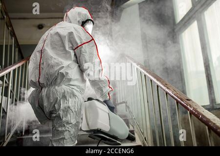 Pandemia di coronavirus, disinfezione contro il virus COVID-19. Disinfettante professionale in abbigliamento protettivo, lotta contro la pandemia di rischio per la salute, remo Foto Stock