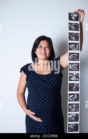 Donna incinta che tiene le scansioni del bambino Foto Stock