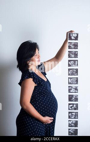 Donna incinta che tiene le scansioni del bambino Foto Stock