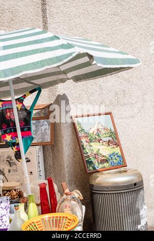 Bancarella del mercato delle pulci con vasi, immagini, costume da bagno e ombrellone di fronte a un muro intonacato Foto Stock