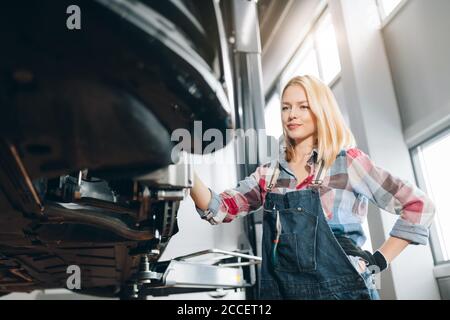 bionda ragazza che si riposa dopo aver riparato una macchina in officina. primo piano foto Foto Stock