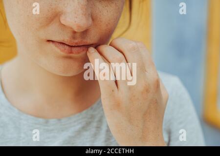 Primo piano ritratto di giovane donna con le frettole che tengono la mano alle labbra Foto Stock