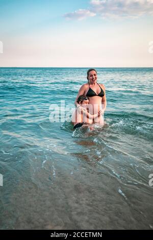 bambino di 5 anni abbracciando madre incinta, vita profonda nell'oceano Foto Stock