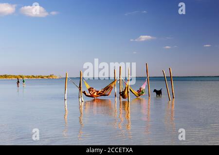 I turisti possono prendere il sole su una spiaggia di Holbox accanto ad alcune amache. Holbox Island, Cancun, Yucatan, Messico Foto Stock