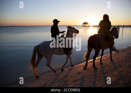 Escursione turistica a cavallo su una spiaggia idilliaca dell'isola di Holbox al tramonto. Yucatan, Messico Foto Stock
