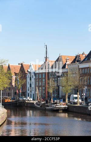 Vista sui canali con le vecchie navi a vela tradizionali e le case storiche nel centro della città di Groningen, Paesi Bassi Foto Stock