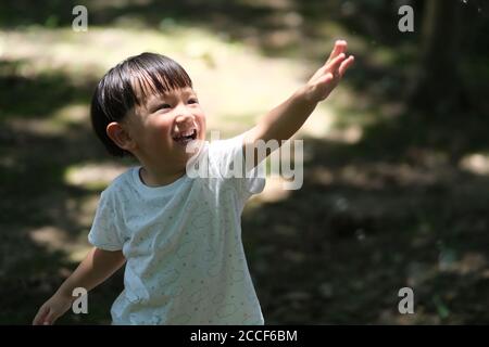 Primo piano un bambino asiatico che alza il braccio al sole. Sfocatura dello sfondo Foto Stock